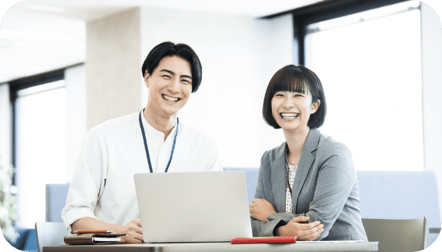 オフィスにてこちらに笑顔を向ける男性と女性