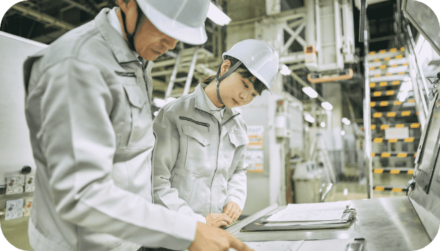 工場で作業をする若い女性と年配の男性