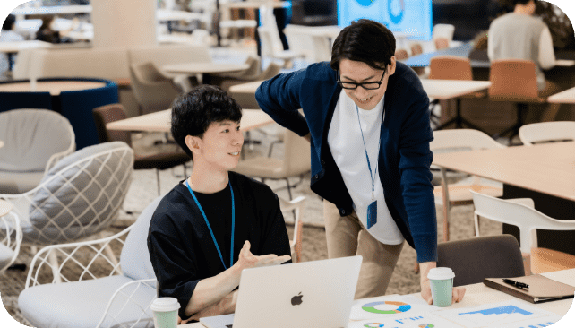 パソコンを見ながら会話をする2人の男性